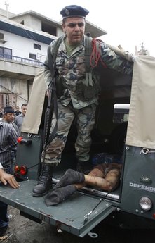A Lebanese soldier stands in an army truck next to the body of Egyptian Mohammed Mosallem that was stabbed to death in Ketermaya village 
